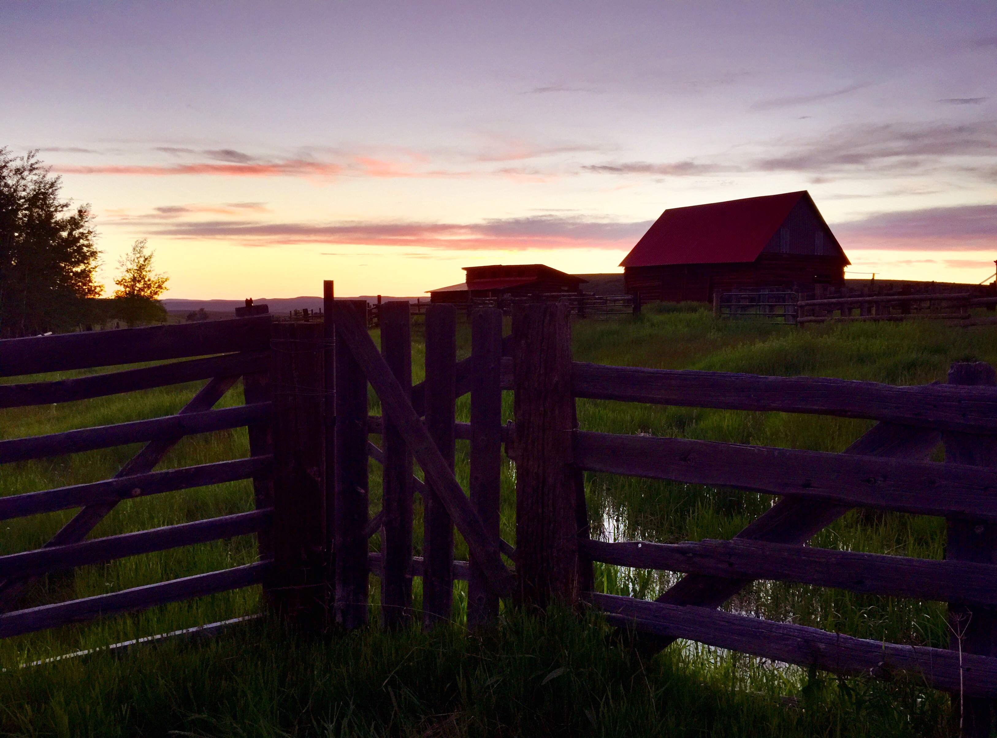 Sunset over ranch barn with wooden fence